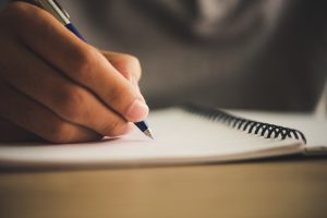 man-hand-with-pen-writing-on-notebook