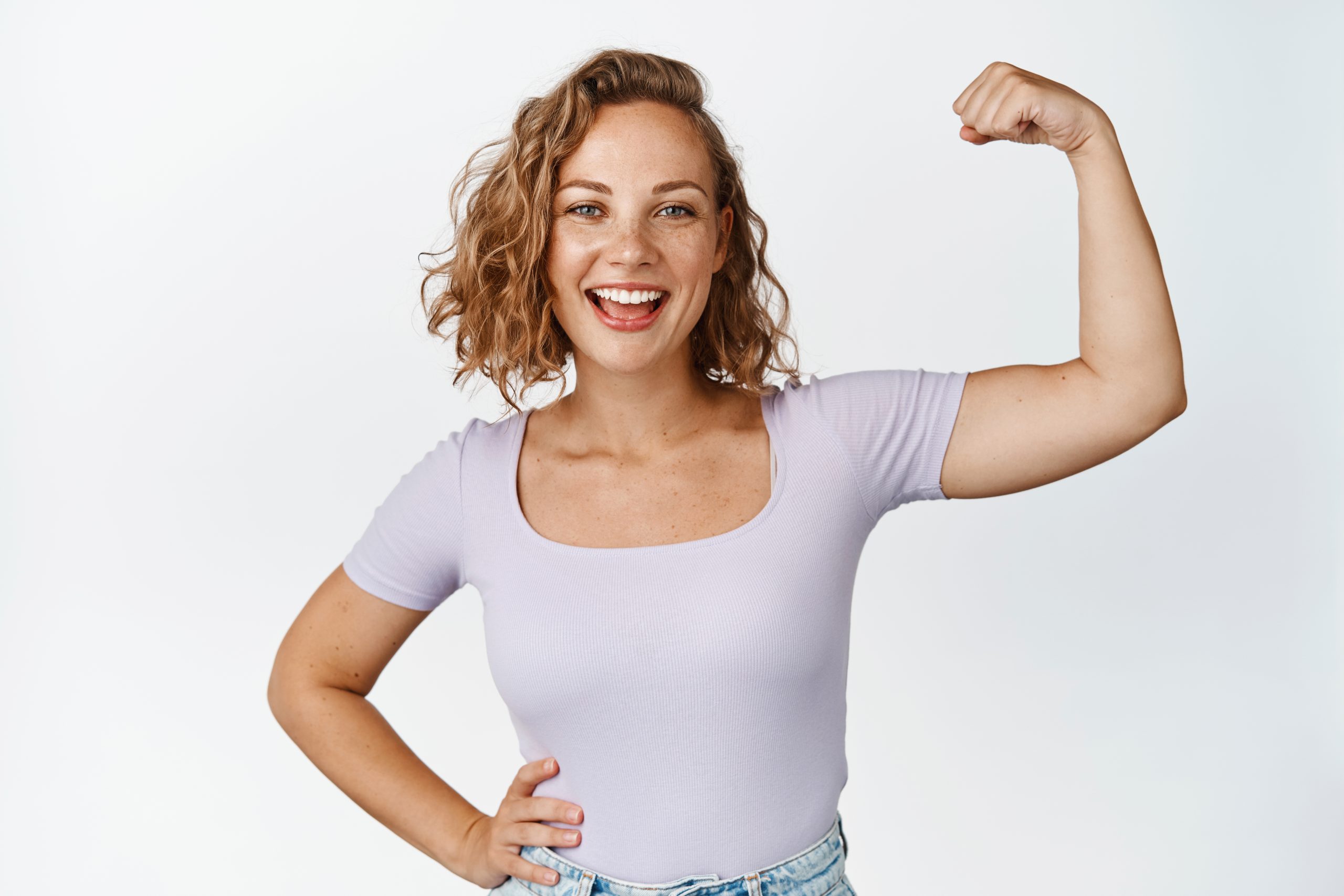 image-of-positive-blond-girl-smiles-flex-biceps-shows-strong-arm-muscles-stands-against-white-background