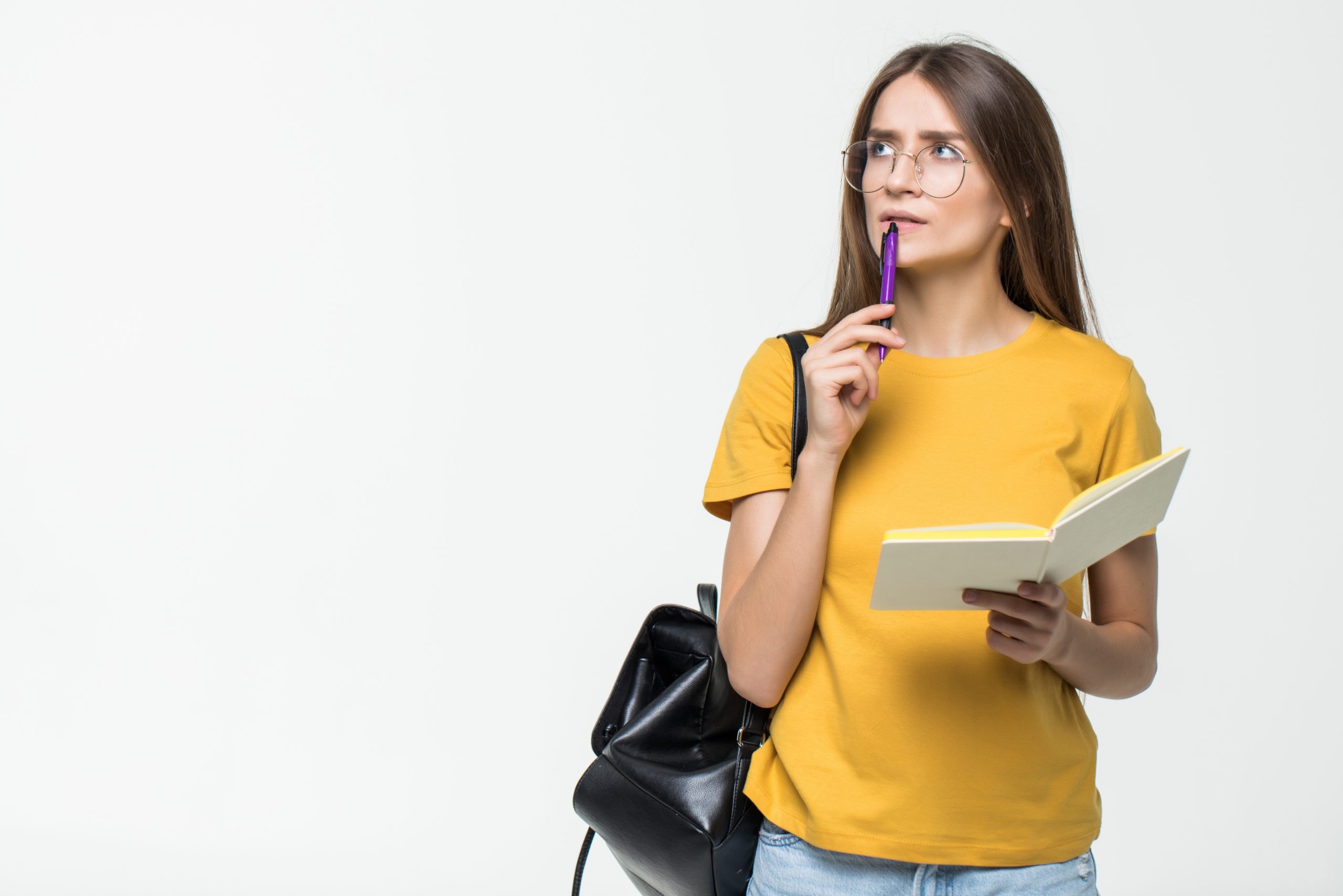 portrait-of-a-smiling-casual-girl-student-with-backpack-writing-in-a-notepad-while-standing-with-books-isolated-over-white-background