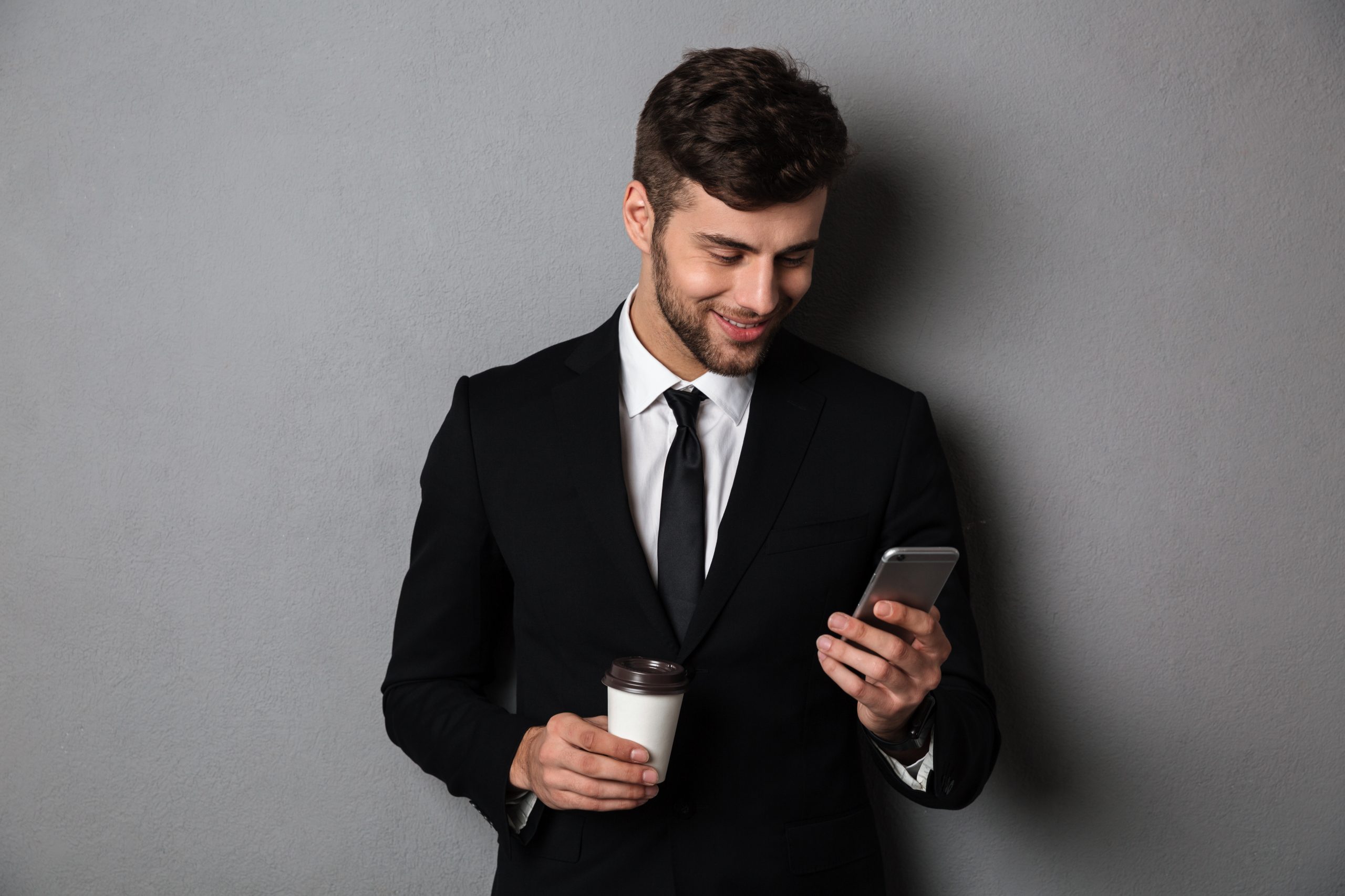 young-handsom-man-in-formal-wear-checking-news-on-smartphone-whi